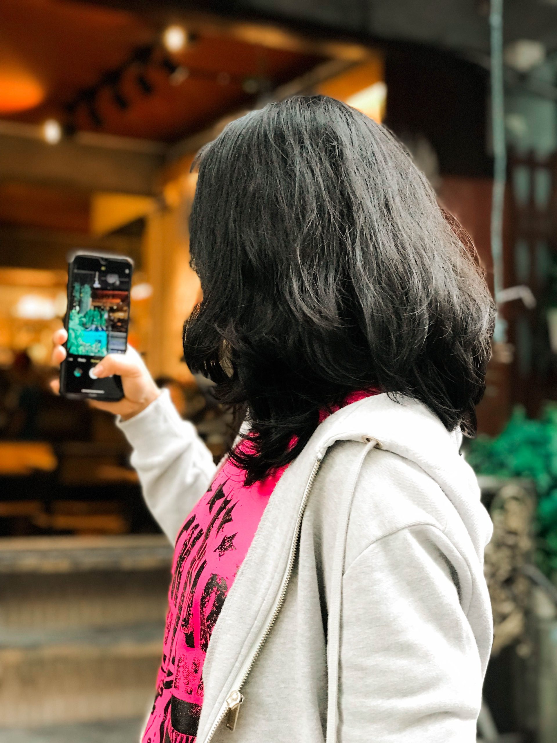 Woman standing outdoors holding up her phone to the screen