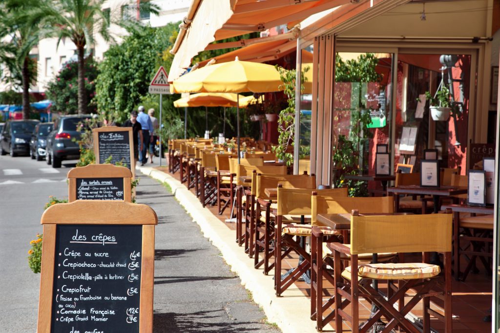 Outdoor cafe terrace with a chalkboard menu on the sidewalk