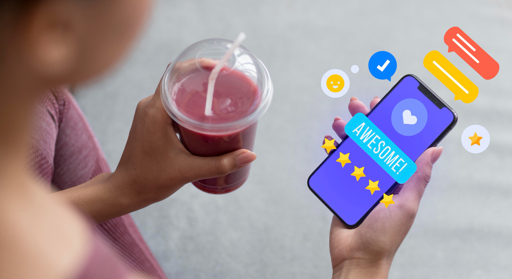 Hand holding a phone showing a five star review notification beside a cold drink